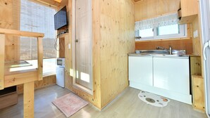Una cabaña de madera compacta con kitchenette, una ventana pequeña y una puerta.