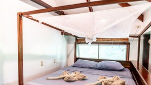A room with a four-poster bed, a mosquito net, and a window with a view. - Greenhouse Siargao (General Luna)