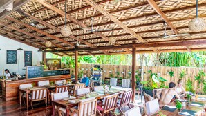 An outdoor restaurant with wooden tables and chairs, a bamboo ceiling, and a menu board. - Greenhouse Siargao (General Luna)