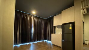 Une cuisine moderne avec un plancher en bois, un réfrigérateur noir et un rideau doté d’un éclairage à LED.