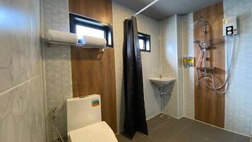 Et moderne badeværelse med toilet, vask og brusebad.