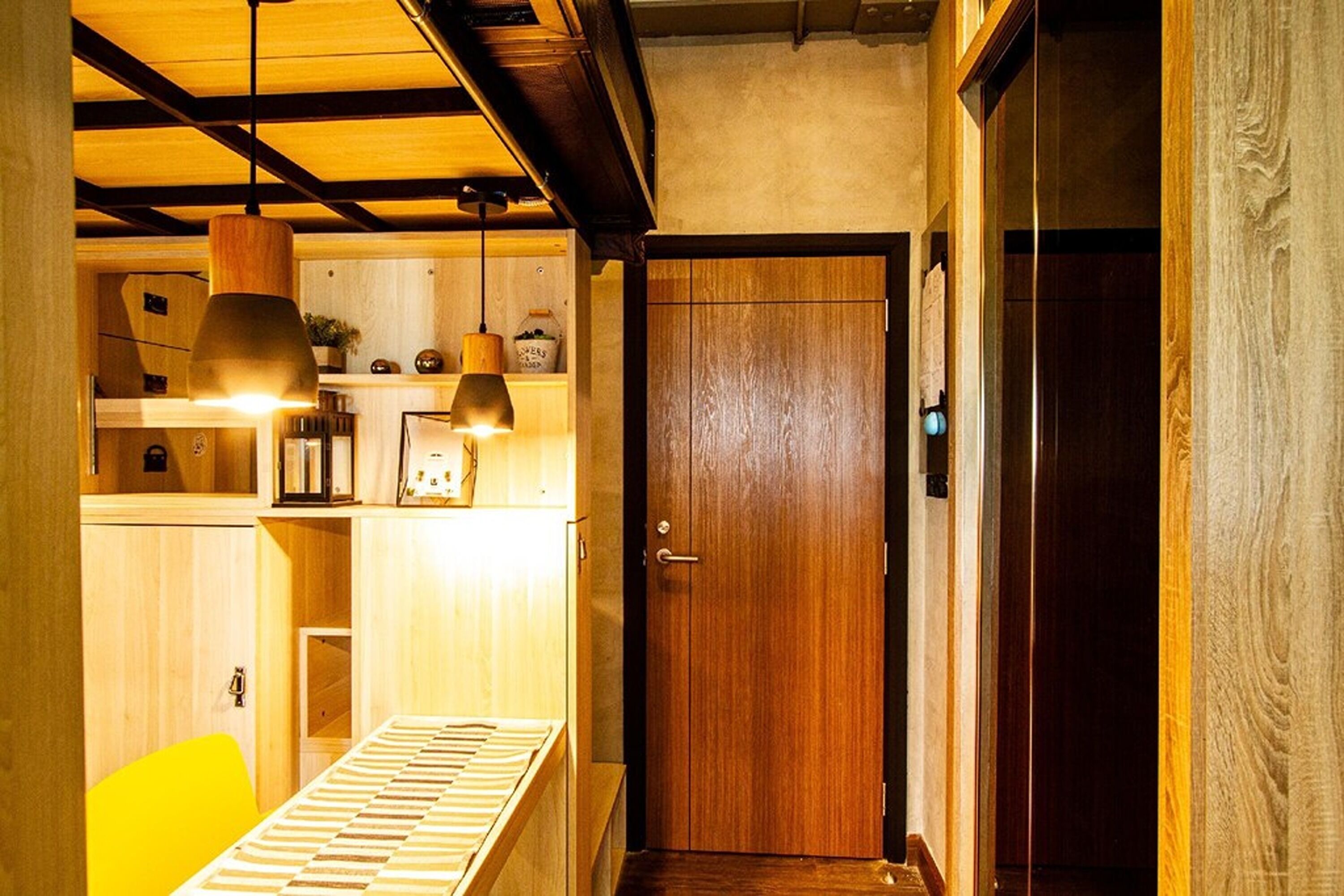 A wooden interior with a dining area, a wooden door, and pendant lighting.