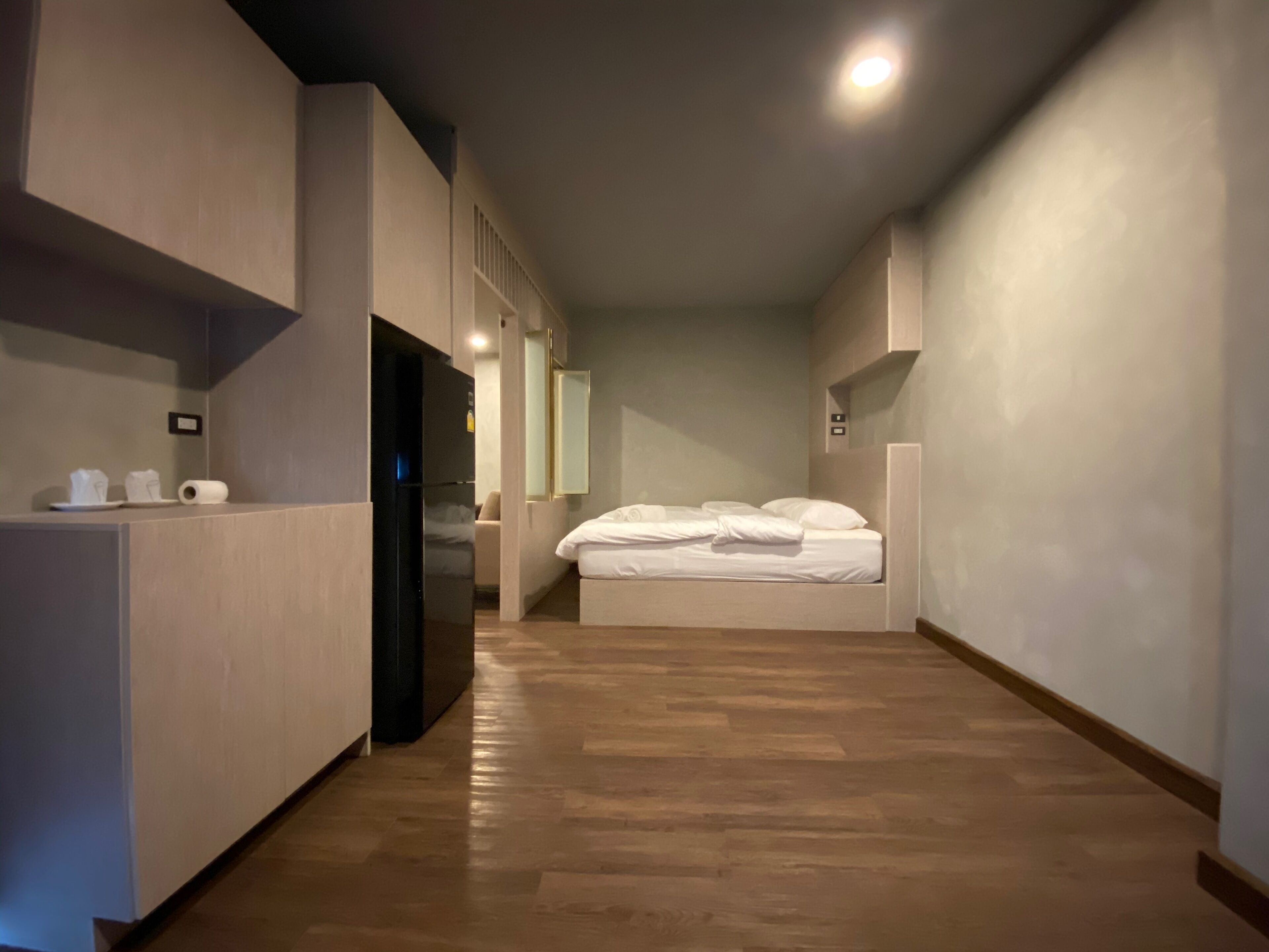 Een hotelkamer met een bed, een kleine kitchenette en een houten vloer.
