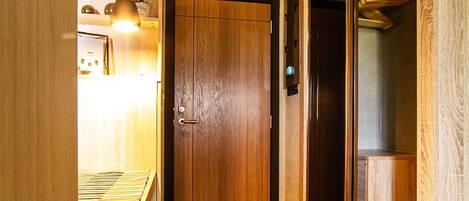 Un pasillo estrecho con suelo de madera y una puerta de madera al final.