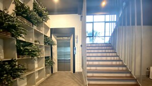 Un intérieur moderne avec un escalier, un paillasson et des étagères ornées de plantes.