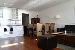 A modern kitchen with white cabinets, a dining area with wicker chairs, and a black leather sofa. - Tysnes Sjø og Fritid (Tysnes)