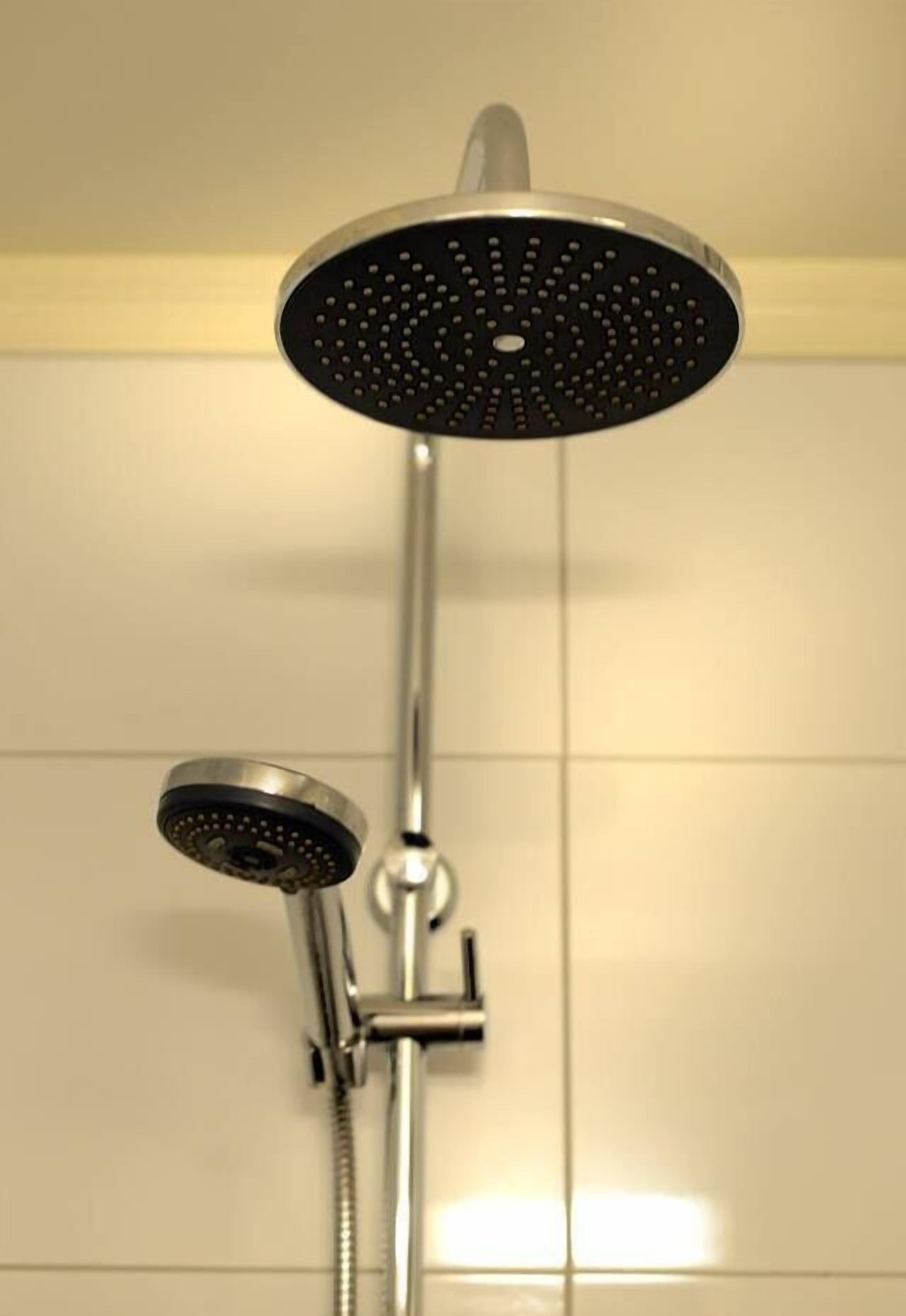 A shower with a round head and a handheld showerhead.