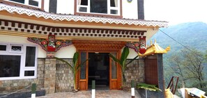 A traditional building with a wooden entrance, decorative elements, and a view of mountains in the background.