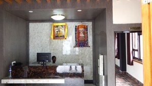 A reception area with a marble counter, a computer, and two framed religious pictures on the wall. - Hotel Shambala Inn (Gangtok)