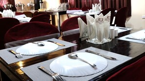 A hotel dining area with tables set for four, each with white plates, silverware, and napkins. - Hotel Shambala Inn (Gangtok)