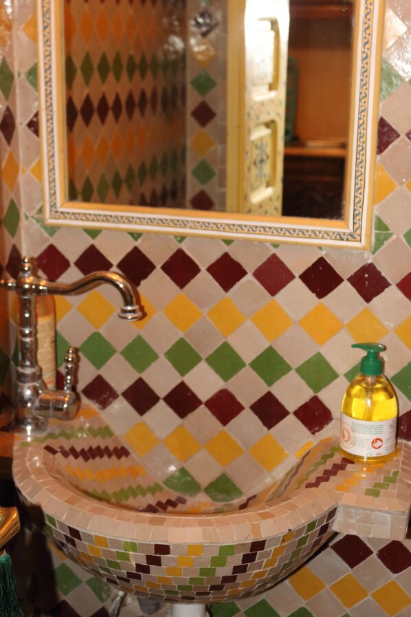 A bathroom with a mosaic tile sink, a mirror, and a bottle of soap. - RIAD THE DOOR OF THE MEDINA ANY COMFORT (Marrakech)