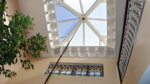 Une pièce dotée d’une lucarne, d’une fenêtre ornée de vitraux et d’une plante.