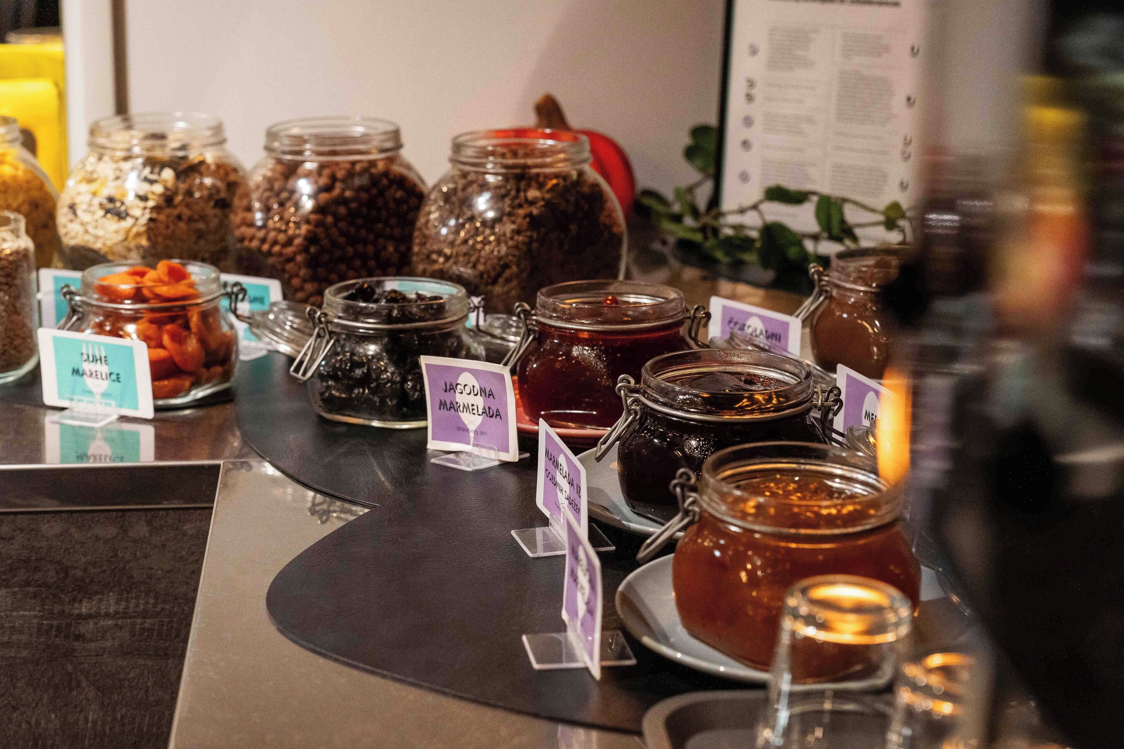 Exhibición de diversos alimentos en frascos con etiquetas, probablemente en un mercado de alimentos o cafetería.