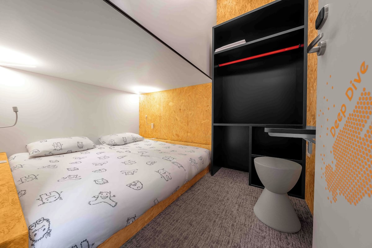 Ein kleines Zimmer mit Bett, eingebautem Kleiderschrank und Toilette.