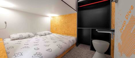 A compact room with a bed, a built-in wardrobe, and a toilet.
