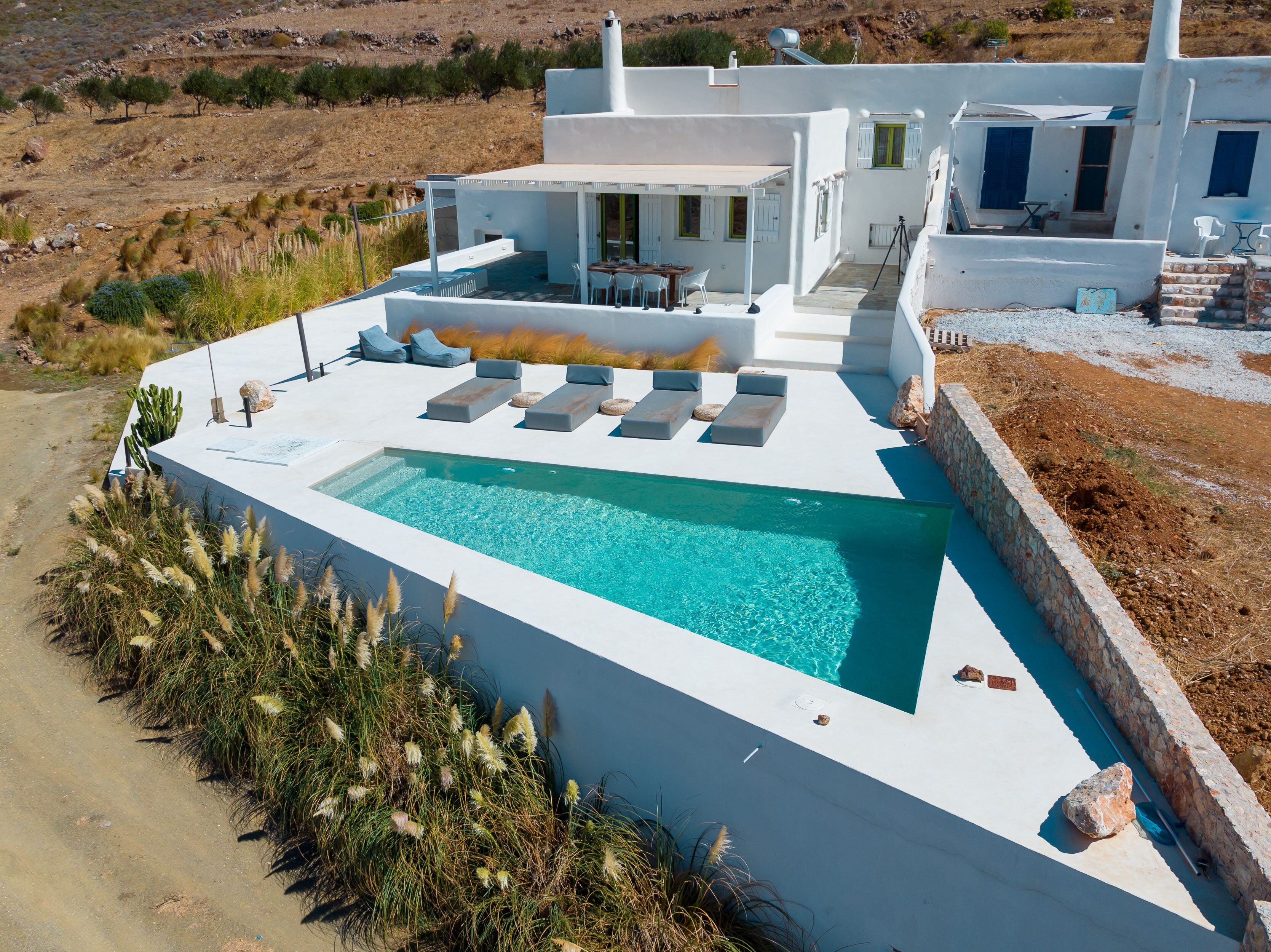 Une maison moderne dotée d’une piscine, d’un espace salon extérieur et offrant une vue sur le paysage environnant.
