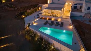 Una piscina al aire libre, sombrillas, sillones reclinables de piscina