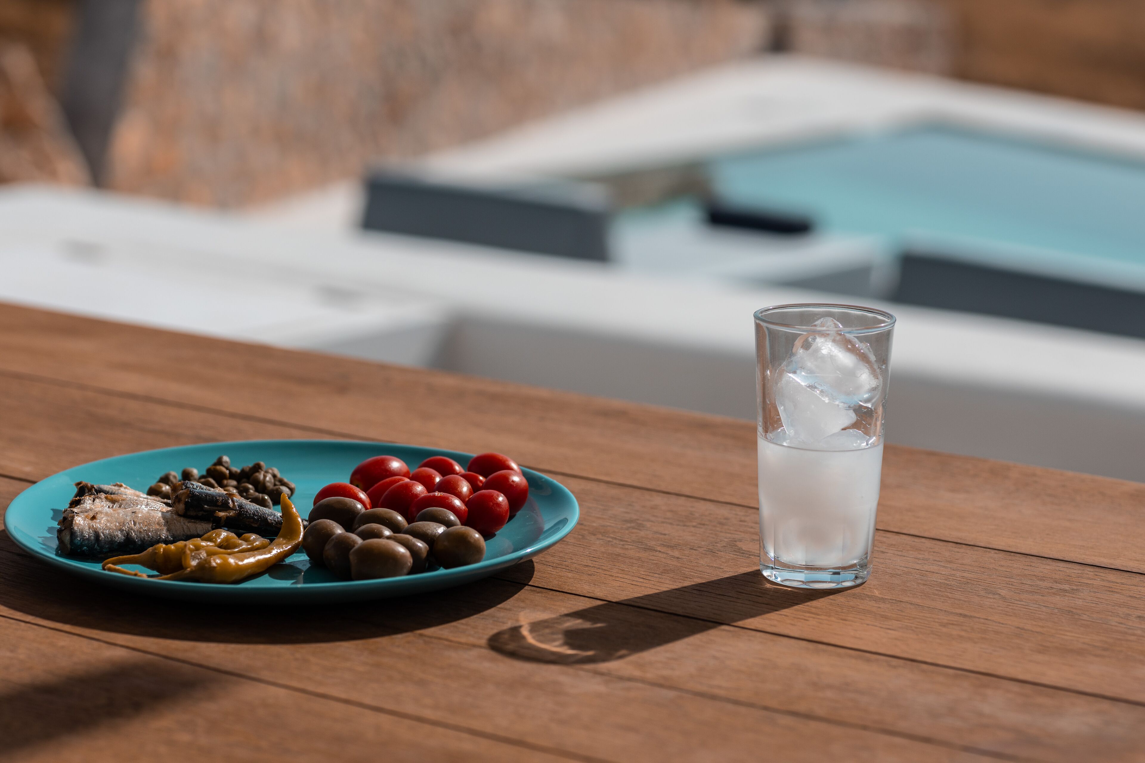 A wooden table with a plate of food and a glass of water.