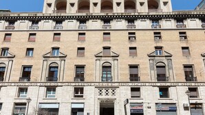 Een meerlaags gebouw met een klassieke architectuur, met bogen in de ramen en balkons op de bovenste verdiepingen.