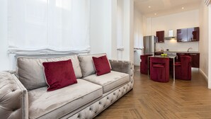 Een moderne woonkamer met een beige bank, rode kussens en een houten vloer.