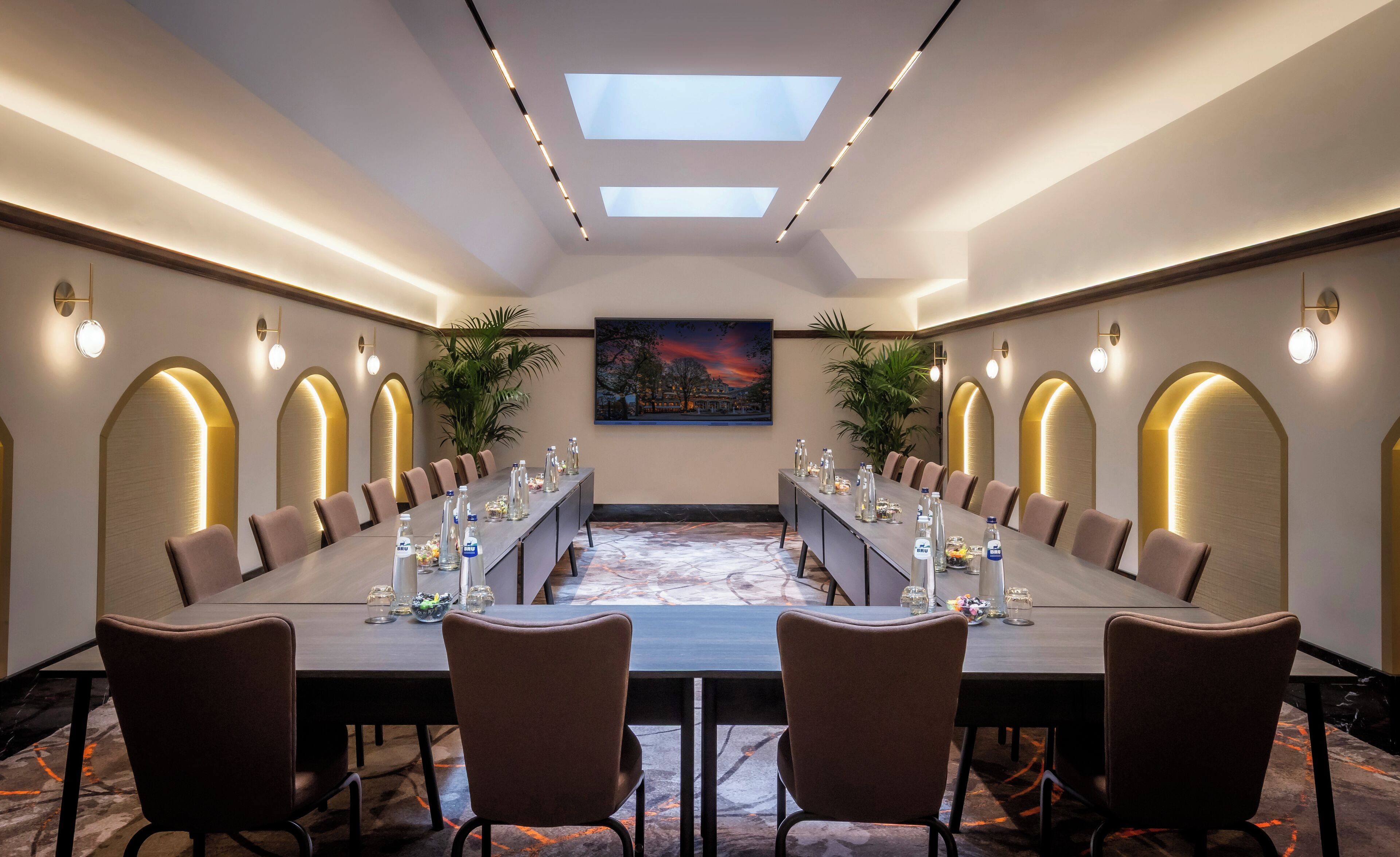 Une salle de conférence avec une longue table, des chaises et un tableau accroché au mur.
