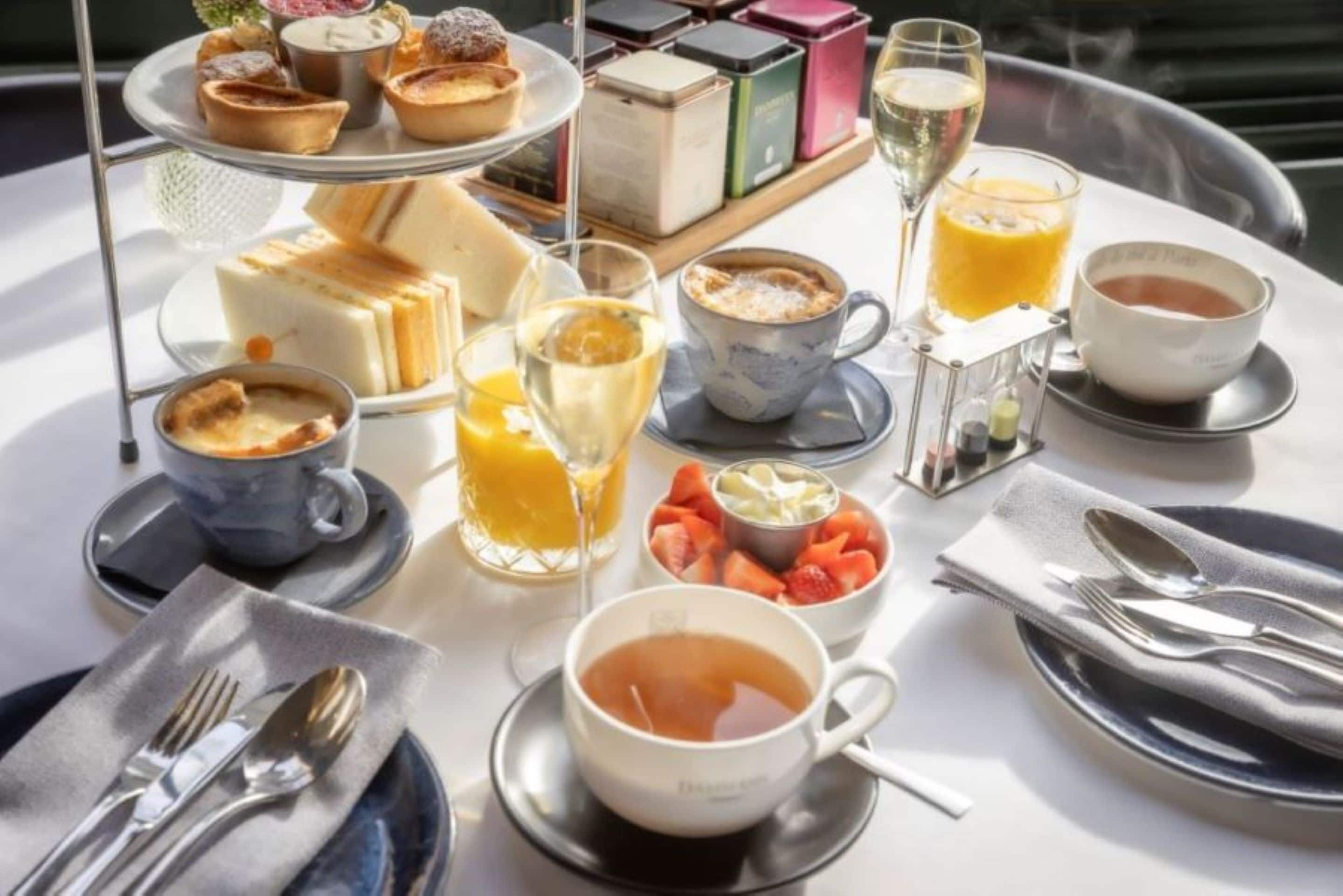 A breakfast setting with a variety of pastries, fruits, and beverages on a table.