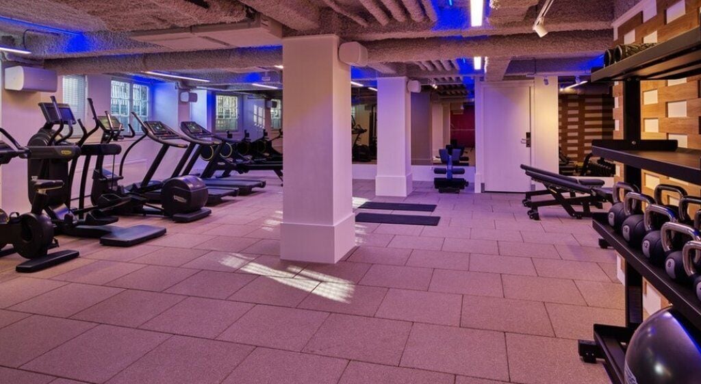 Un gimnasio con cintas de correr, elípticas y bancos de pesas.