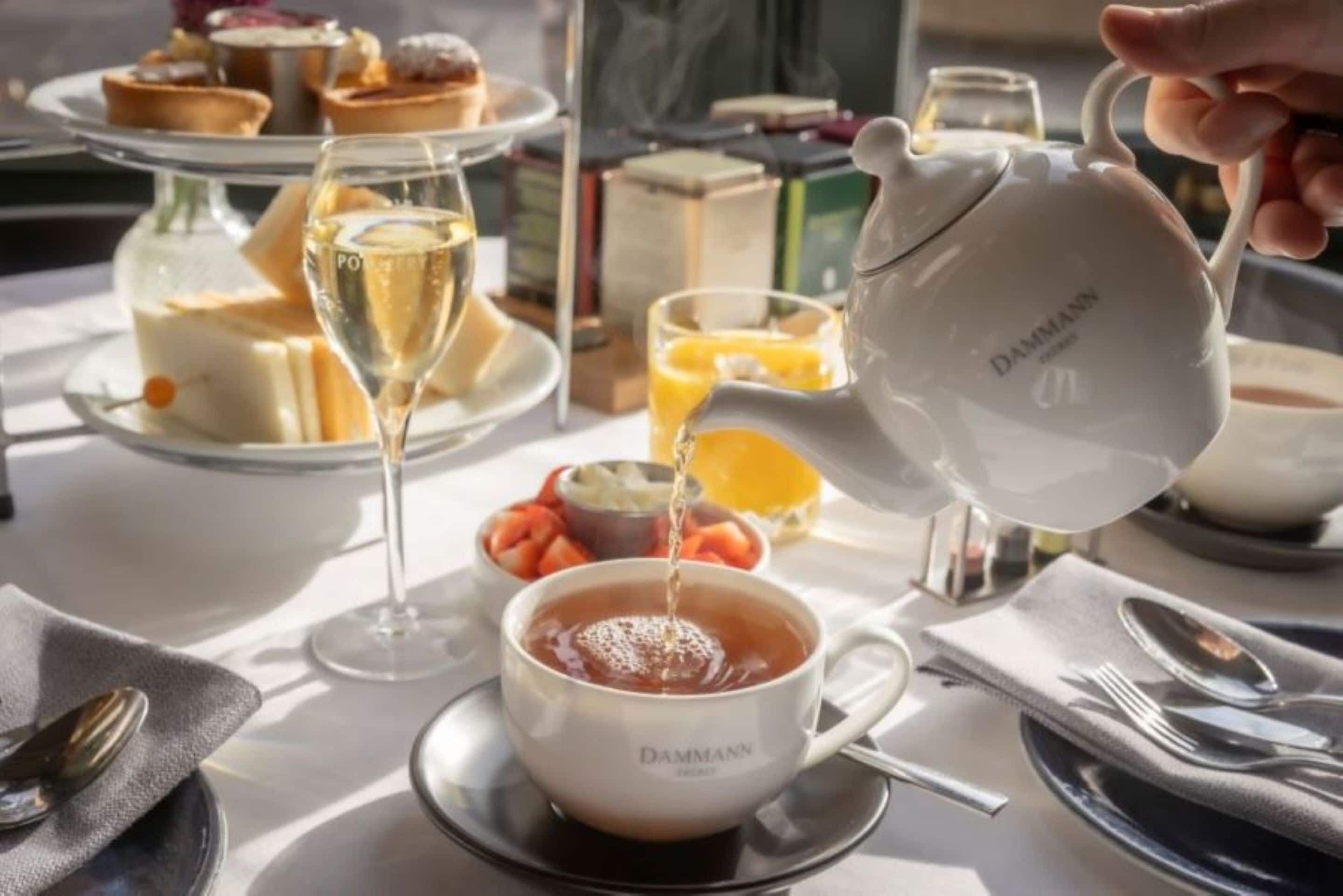 A table set for breakfast with a teapot, cups, and a variety of pastries.