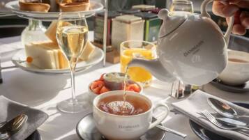 A table set for breakfast with a teapot, cups, and a variety of pastries.