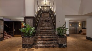 Eine prachtvolle, aus Marmor errichtete Treppe im modernen Stil, gesäumt von Topfpflanzen und beleuchtet von Wandleuchten.