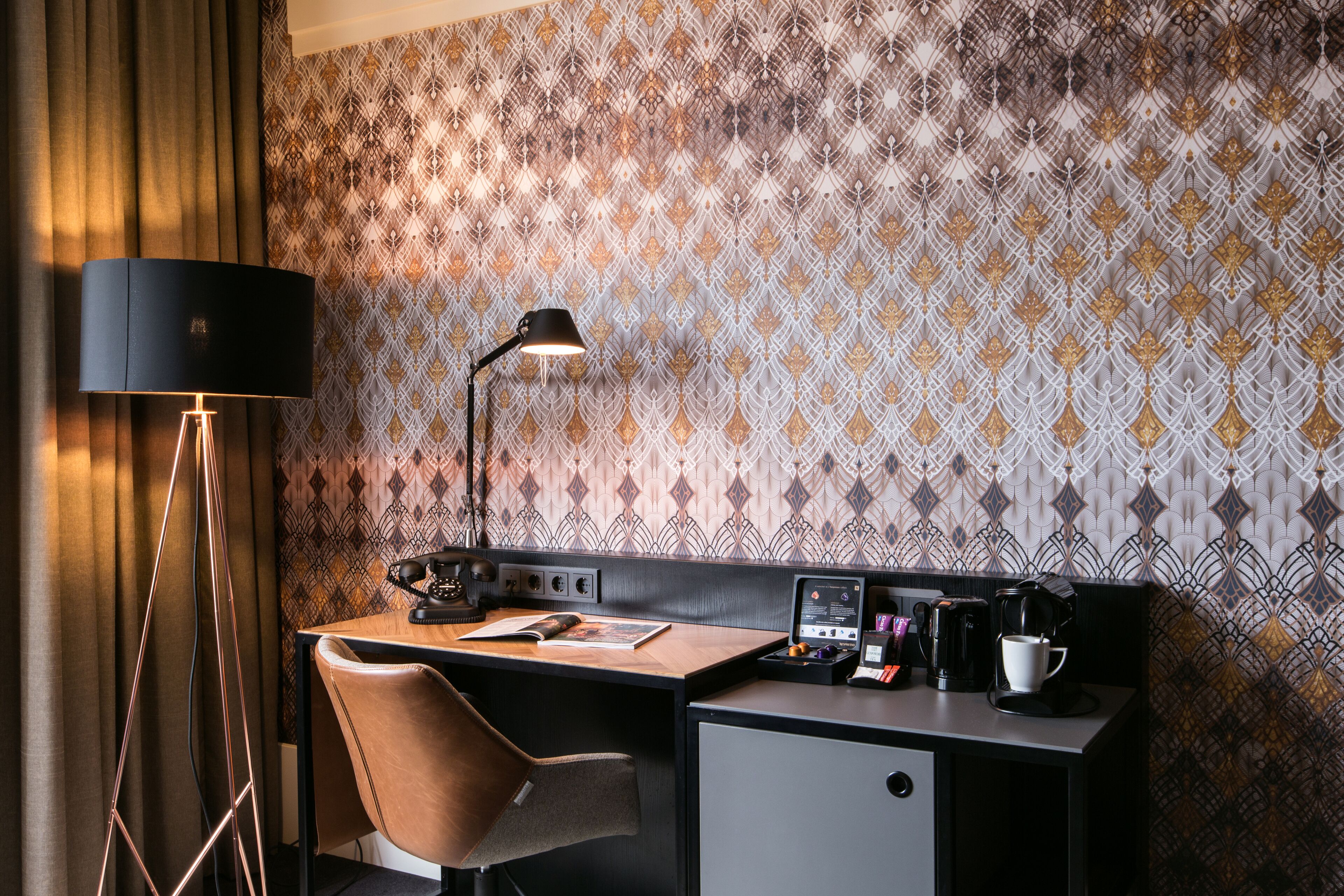 Una habitación de hotel moderna con escritorio, silla, lámpara y cafetera.