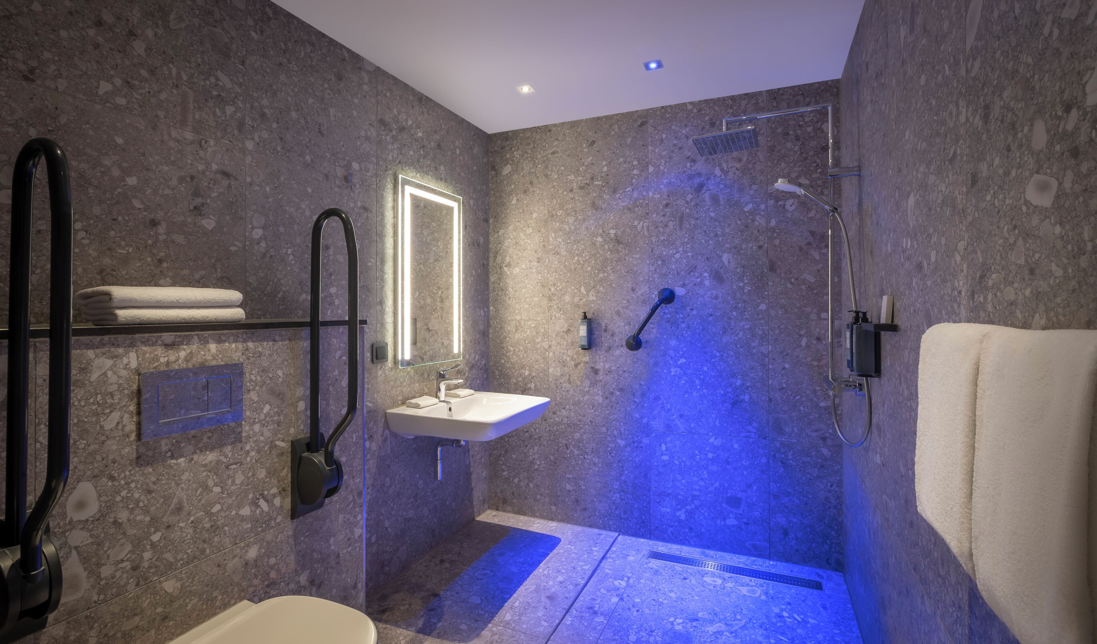 Un baño moderno con ducha envuelta en vidrio, un lavabo blanco y un espejo grande.