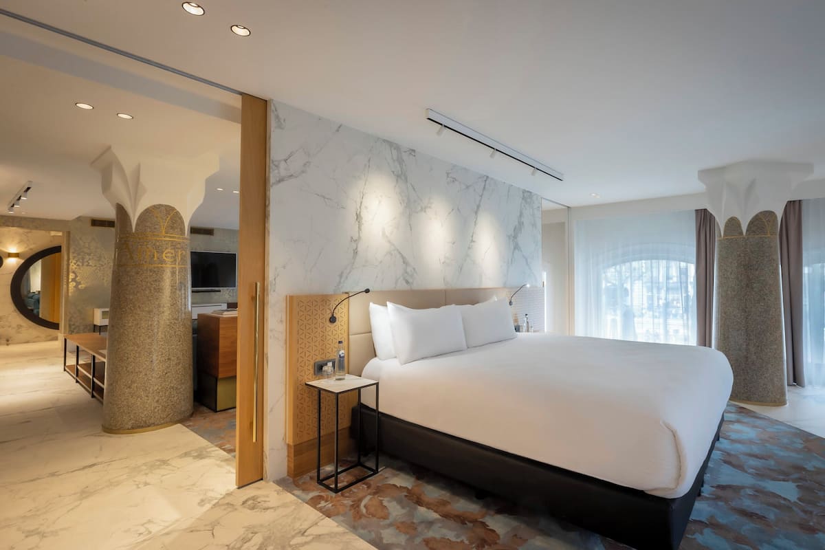 Une chambre d’hôtel moderne avec un grand lit, des murs en marbre et une vue sur la ville.
