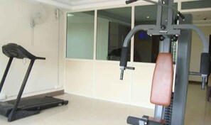 Un gimnasio con cinta de correr y máquinas de pesas.