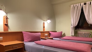 A bedroom with two beds, wooden nightstands, a desk, and a radiator. - Quickborner Hof (Quickborn)