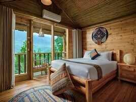 Una habitación de madera con una cama, una mesita de noche, una lámpara colgante y vistas al exterior.
