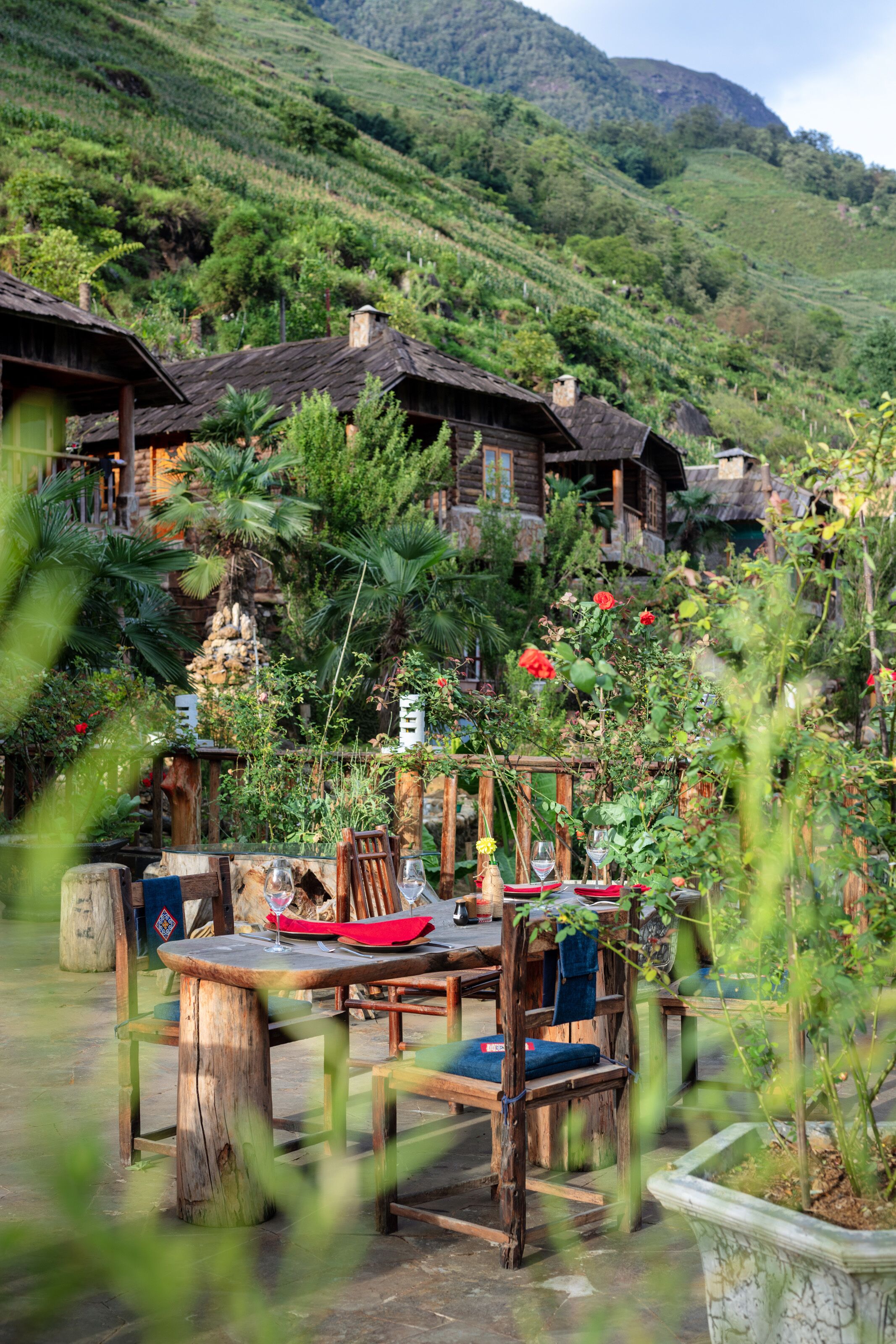 Un espace de restauration en plein air au décor rustique, avec des meubles en bois et une vue sur des maisons traditionnelles situées sur une colline.