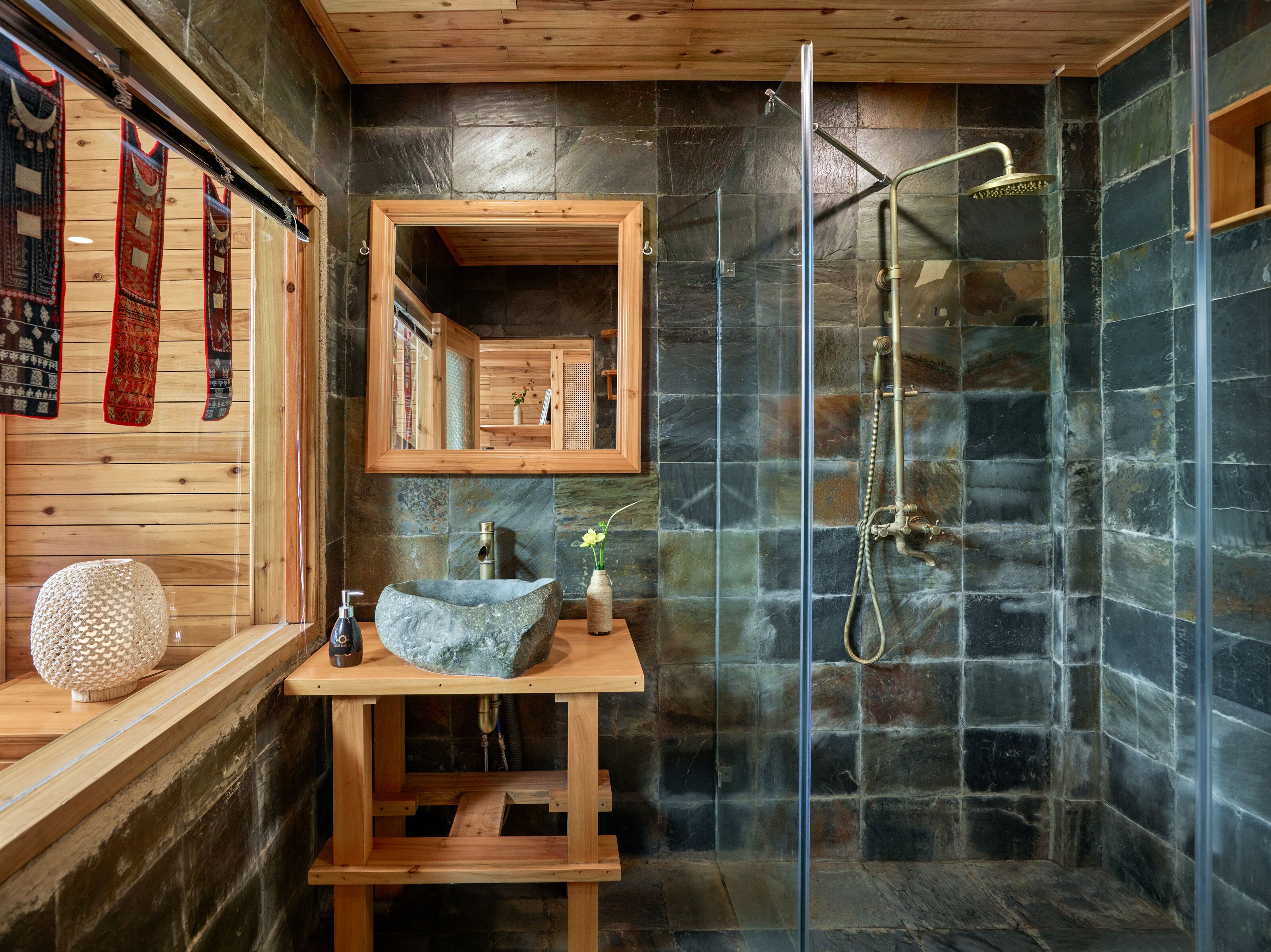 Un baño moderno con ducha de piedra, tocador de madera y espejo.