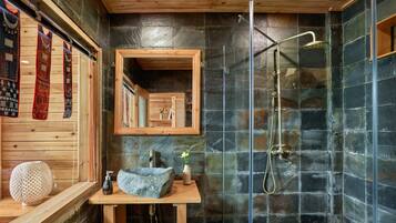 Un baño moderno con ducha de piedra, tocador de madera y espejo.