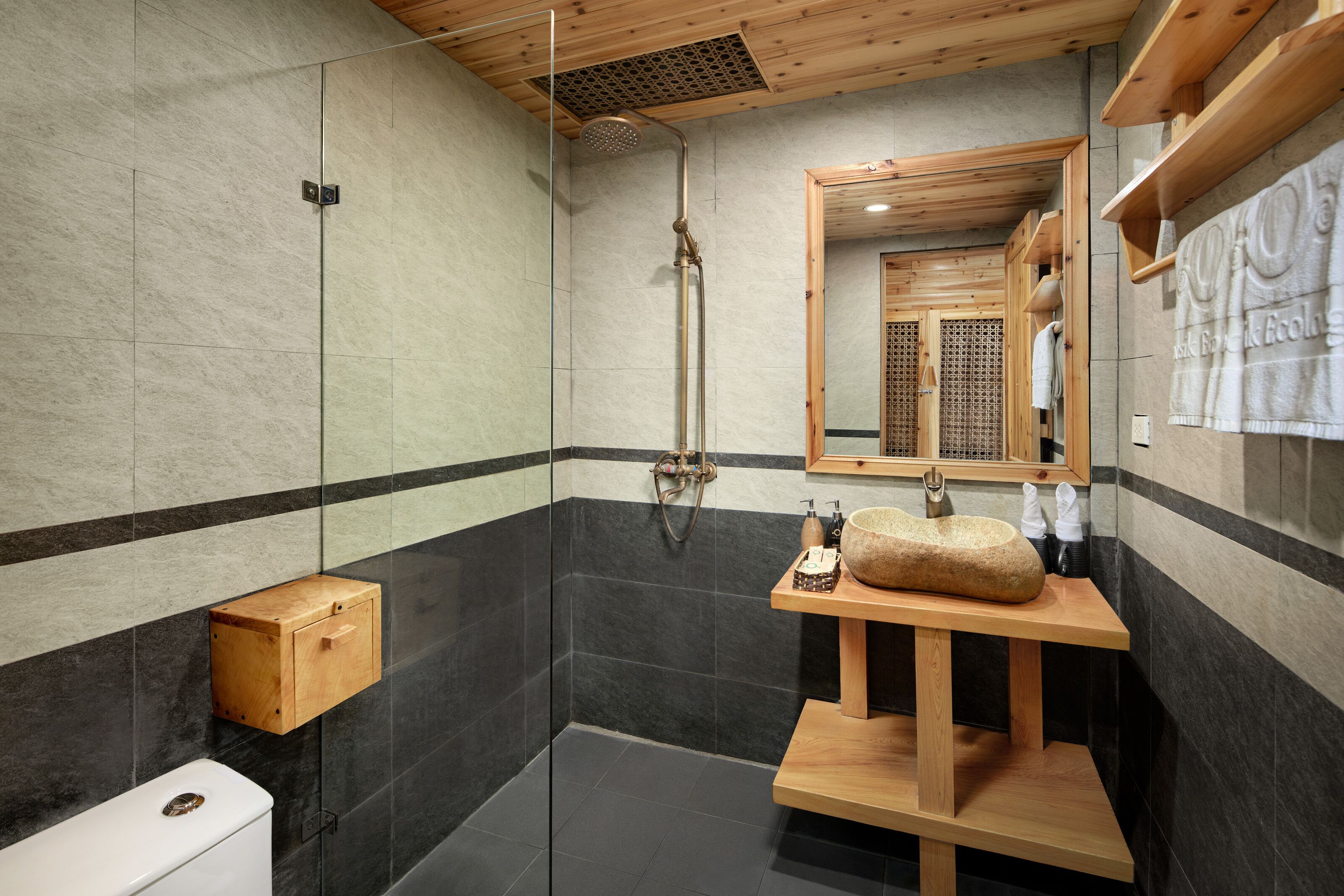 Une salle de bain moderne avec une douche à parois de verre, un meuble-lavabo en bois avec un vasque en pierre et un miroir au-dessus du lavabo.