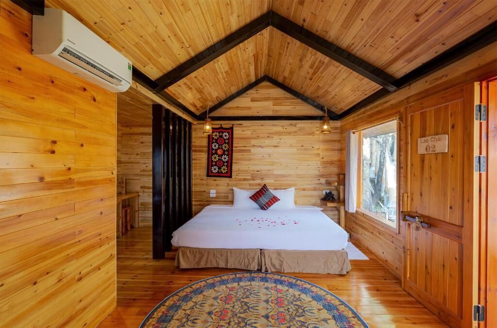 A wooden cabin bedroom with a bed, a rug, and a wall hanging.