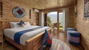 Un dormitorio de cabaña de madera con una cama grande, una mesita y vistas a las montañas.