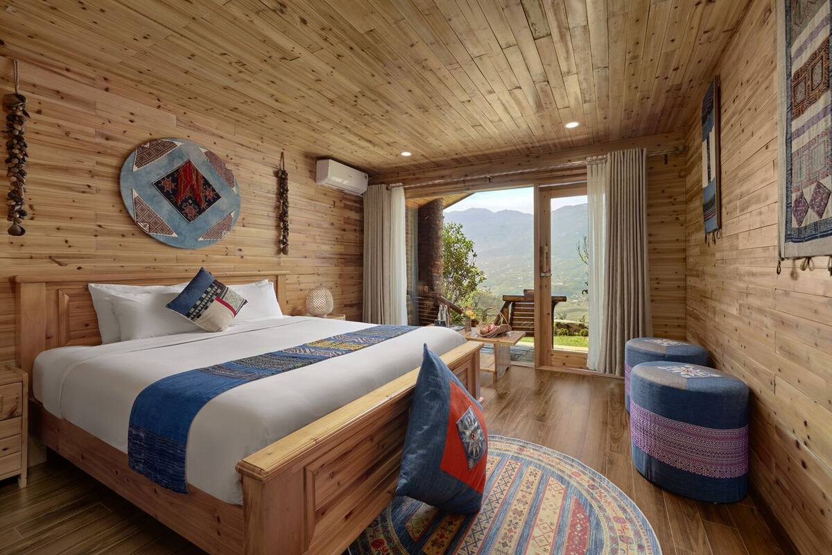 Une chambre aménagée dans une cabane en bois, avec un grand lit, une petite table et une vue sur les montagnes.
