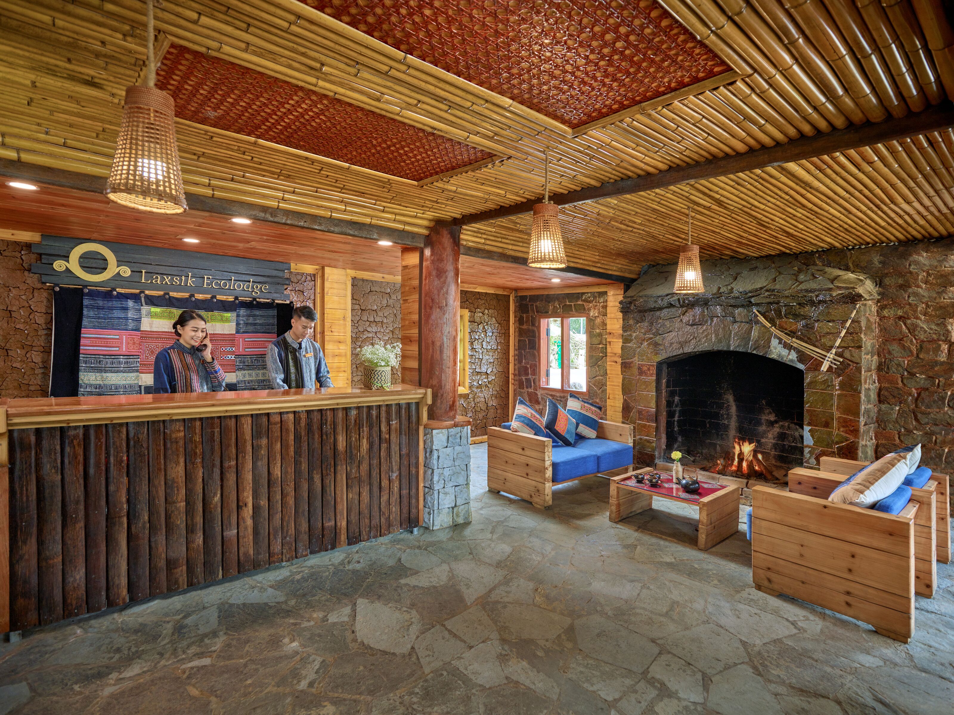 A reception area with a wooden reception desk, a stone fireplace, and a stone floor.