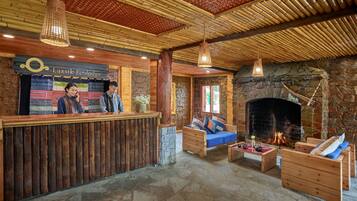 A reception area with a wooden reception desk, a stone fireplace, and a stone floor.