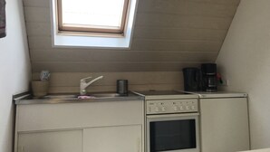 Una cocina compacta con ventana, un lavamanos, una cafetera y una estufa.