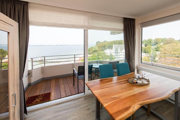 Une pièce avec une table en bois, des chaises et une vue sur la mer.