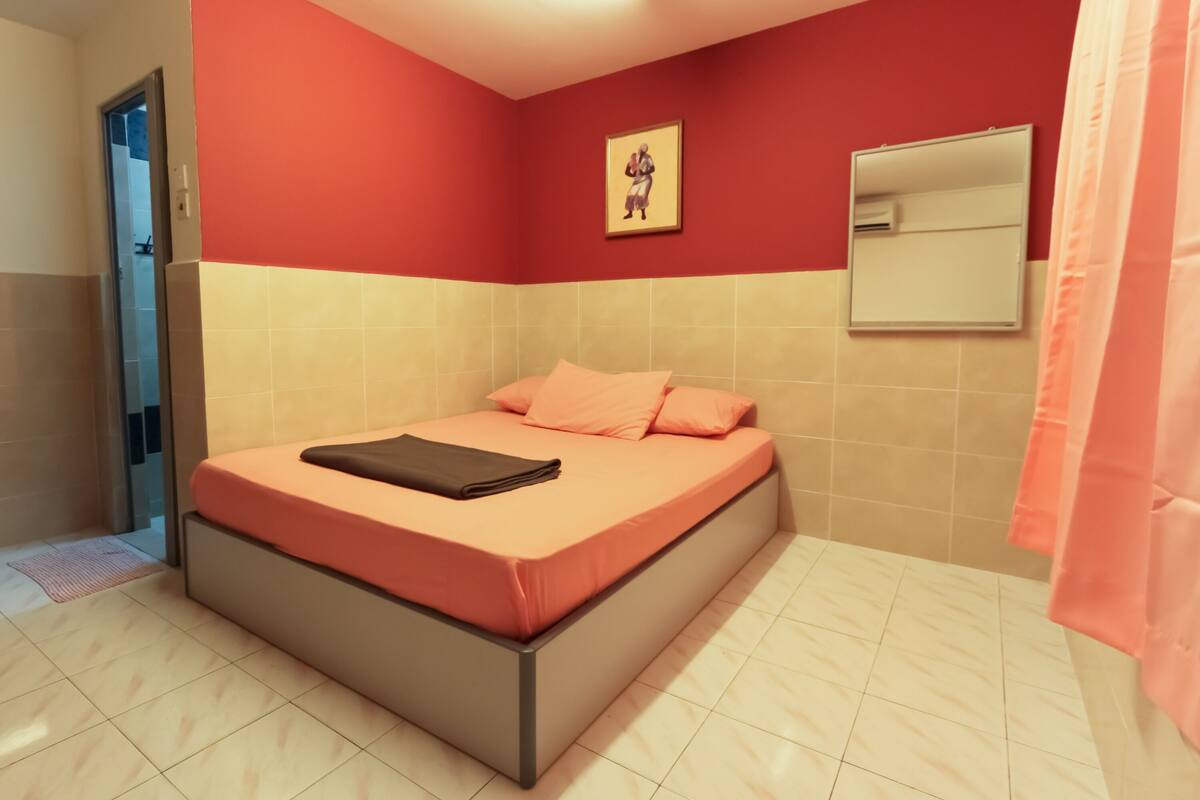 A bedroom with a bed, a door, a wall-mounted mirror, and a framed picture.
