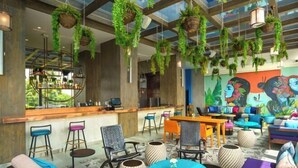 Un espace de détente moderne agrémenté de plantes suspendues, de sièges aux couleurs vives et d’un bar offrant une vue sur l’extérieur.