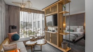 Une chambre d’hôtel moderne équipée d’un canapé, d’une table à manger, d’un téléviseur et d’une grande fenêtre.